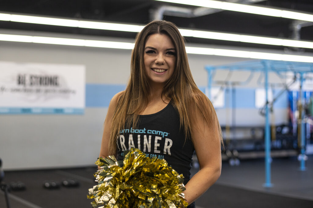 Image description: Portrait of Sara Simpson with pompoms in a gym. End of alt text. 