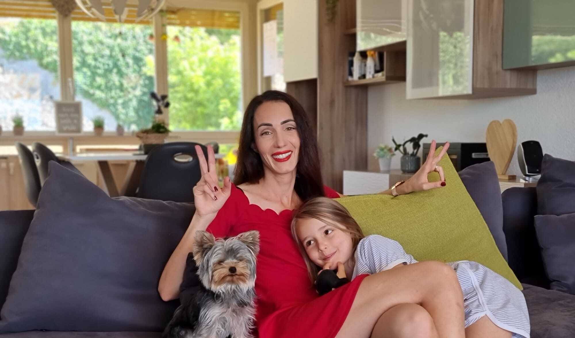 a working mother and her child curl up with the family dog on a sofa in switzerland